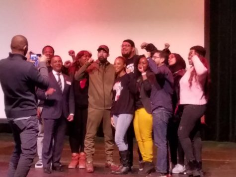 Hip hop artist poses with students, faculty and college president.